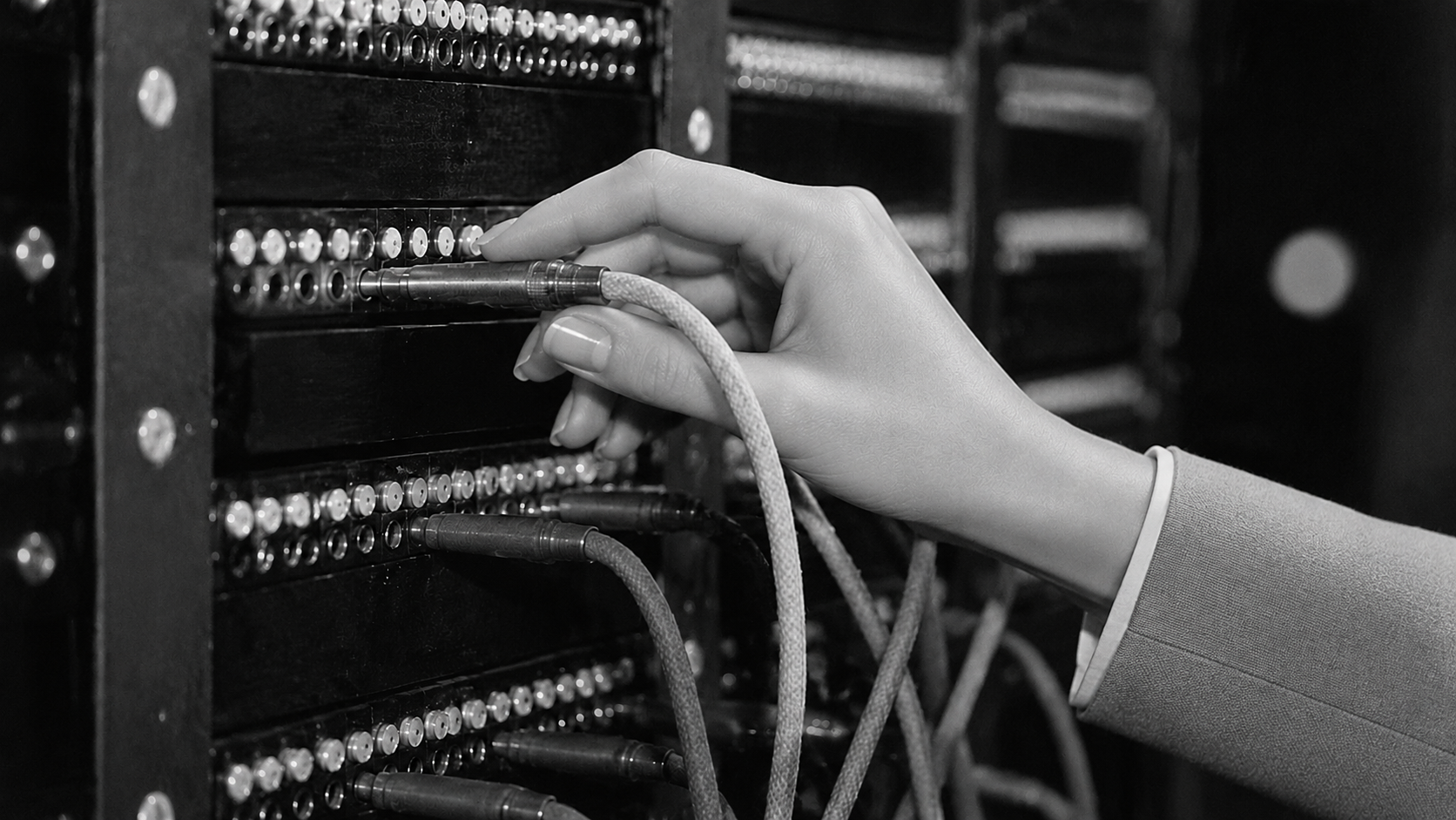 A hand connecting a cable to a vintage telephone switchboard
